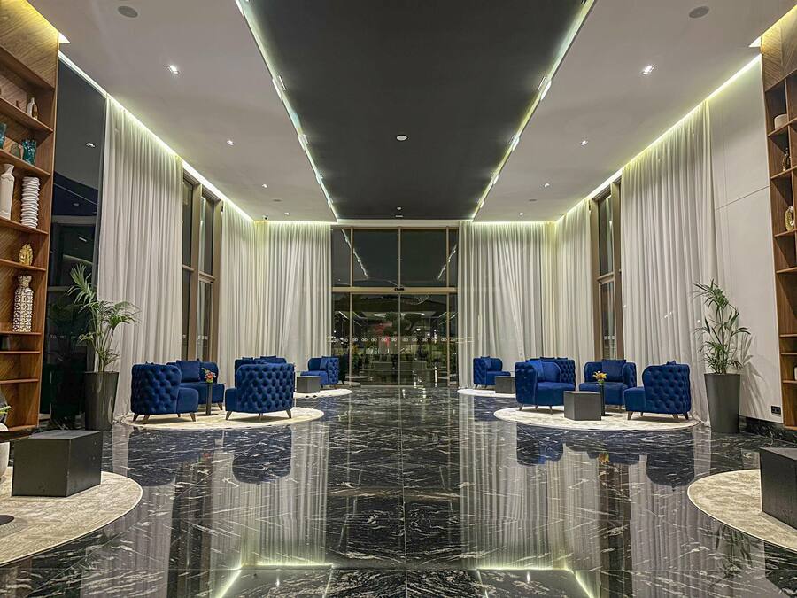 Un hall d’entrée doté d’un sol en marbre, de sièges recouverts d’un tissu bleu et d’un design moderne au niveau du plafond.