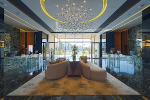 Eine moderne Lobby mit einer zentralen Sitzecke, einem Kronleuchter und Blick durch große Fenster.