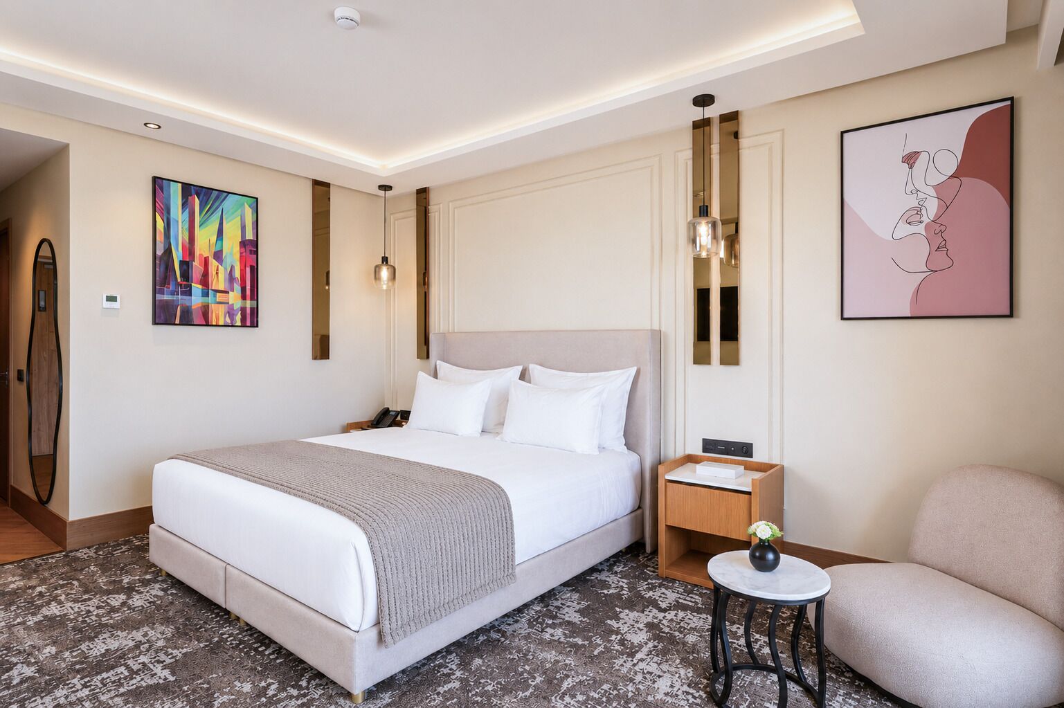 Une chambre d’hôtel avec un grand lit, une table de chevet, une chaise et des œuvres d’art accrochées aux murs.
