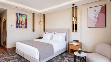 Une chambre d’hôtel avec un grand lit, une table de chevet, une chaise et des œuvres d’art accrochées aux murs.
