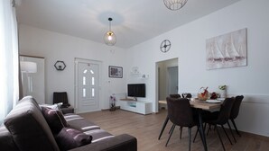 A modern living room with a sofa, TV, dining table, chairs, and artwork on the walls. - Batur Pool Apartment A3, Zadar, Croatia (Zadar)