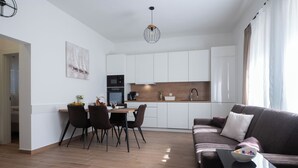 A modern kitchen with white cabinets, a dining area with a table and chairs, and a living area with a sofa and a coffee table. - Batur Pool Apartment A3, Zadar, Croatia (Zadar)