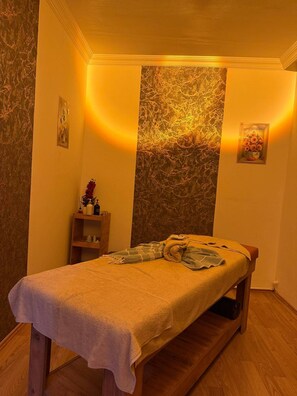 A massage room with a wooden bench, a wall-mounted shelf with toiletries, and a decorative wall panel. - nora palace hotel (Develi)