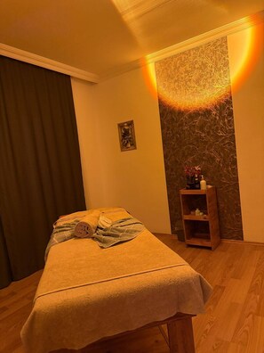 Una habitación con una cama, un pequeño estante con artículos de aseo, una luz de pared y una cortina.