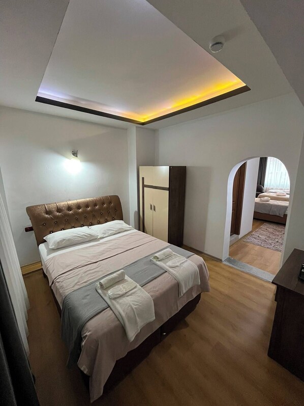 A bedroom with a bed, wardrobe, and a view through an archway.