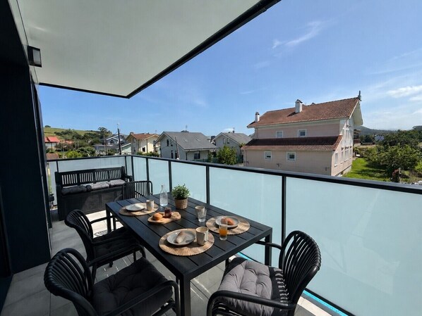 Un balcon avec une table préparée pour le petit-déjeuner, des sièges pour profiter de l’extérieur et une vue sur les bâtiments environnants.