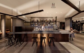 A modern bar area with a long counter, stools, and a wine rack in the background.