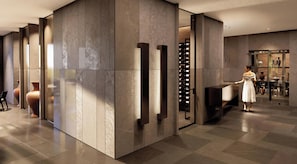 A modern interior with a large stone wall, a wine rack, and a seating area with a table and chairs.