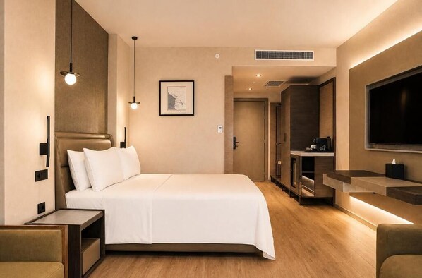 A modern hotel room with a large bed, bedside tables, a flat-screen TV, and a small kitchenette. - CHAONIAN Hotel (Himare)