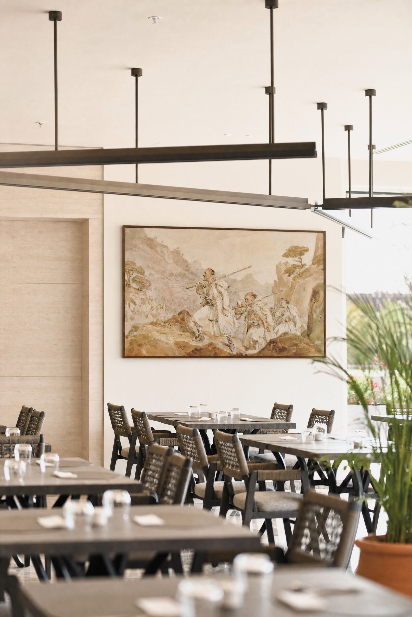 Interior de restaurante con un cuadro clásico grande en la pared, mesas y sillas de madera.