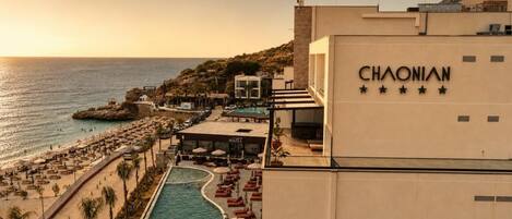 Ein Hotel namens CHAONIAN mit Poolbereich, Liegestühlen am Strand und Meerblick.