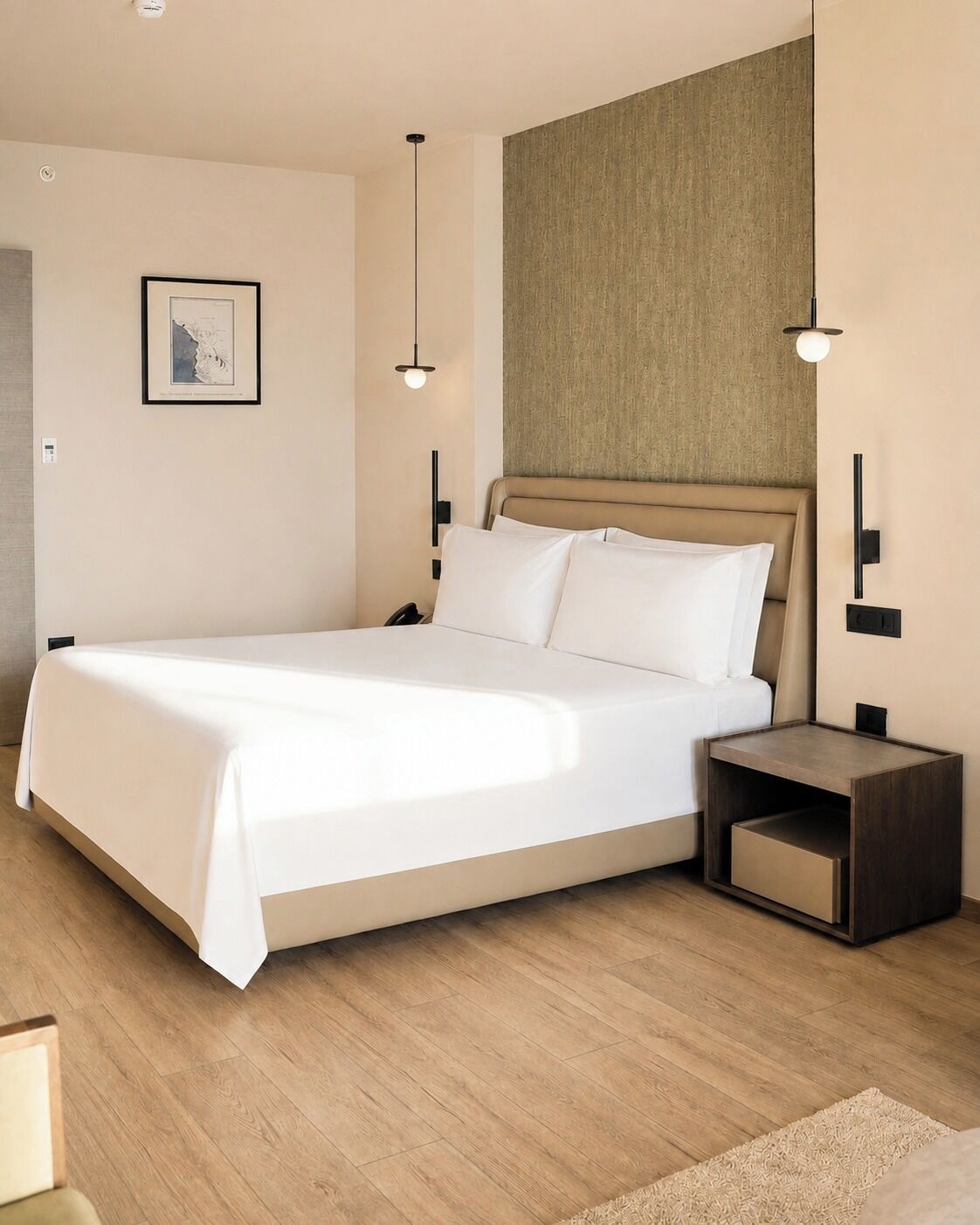 A modern hotel room with a large bed, bedside tables, a wall-mounted light fixture, and a framed picture on the wall.