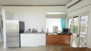 A compact kitchen with a refrigerator, microwave, sink, and wooden cabinets. - TLV Market Apartment (tel aviv)
