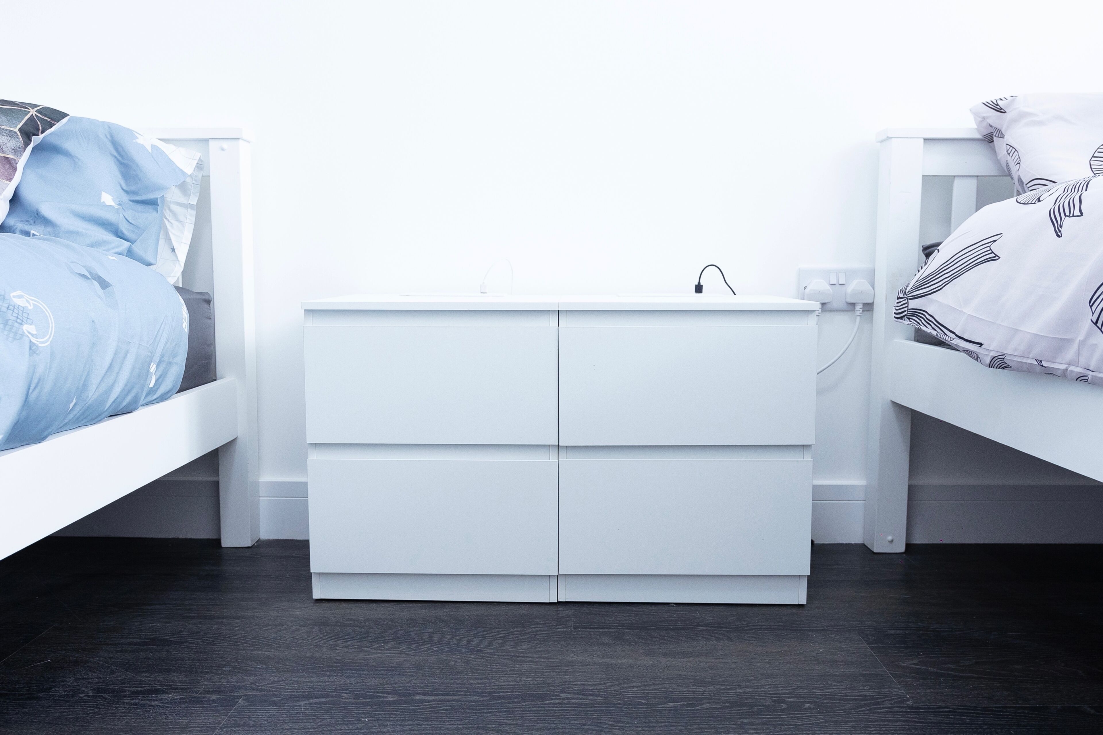 A bedroom with a white bed, a white nightstand, and a white dresser.