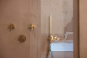 Una habitación con una cama, una lámpara fijada en la pared y una puerta con manija.