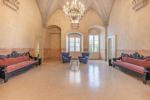 A spacious lobby with a high ceiling, ornate chandeliers, and a red and black sofa set.