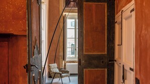 A hallway with a chair, a window, and a door.