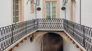 A white building with a central staircase, a balcony, and a decorative ceiling.