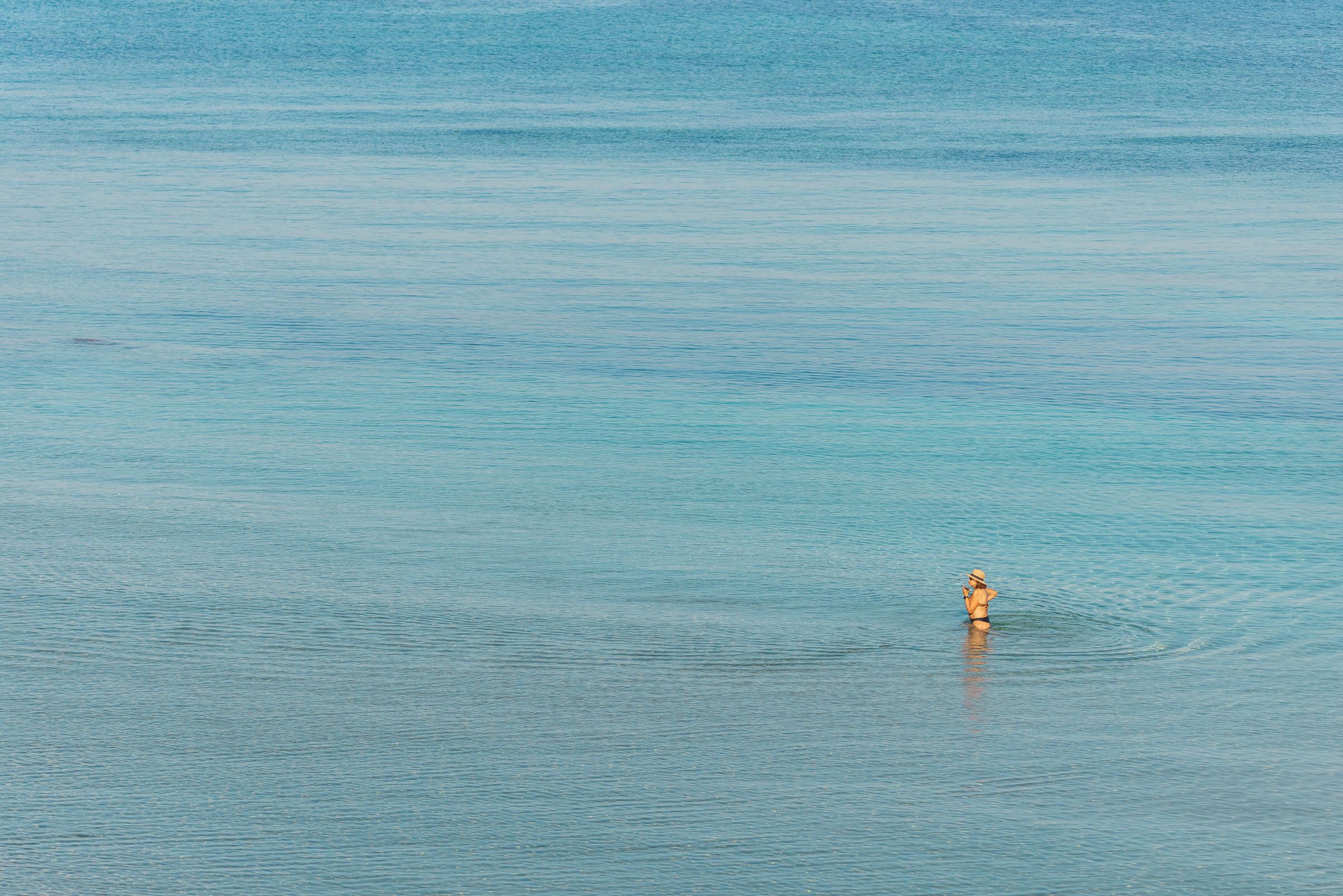 A person in a swimsuit standing in calm water.
