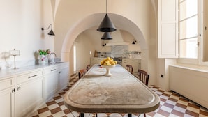 A kitchen with a checkered floor, white cabinets, a central island with a bowl of lemons, and pendant lighting.