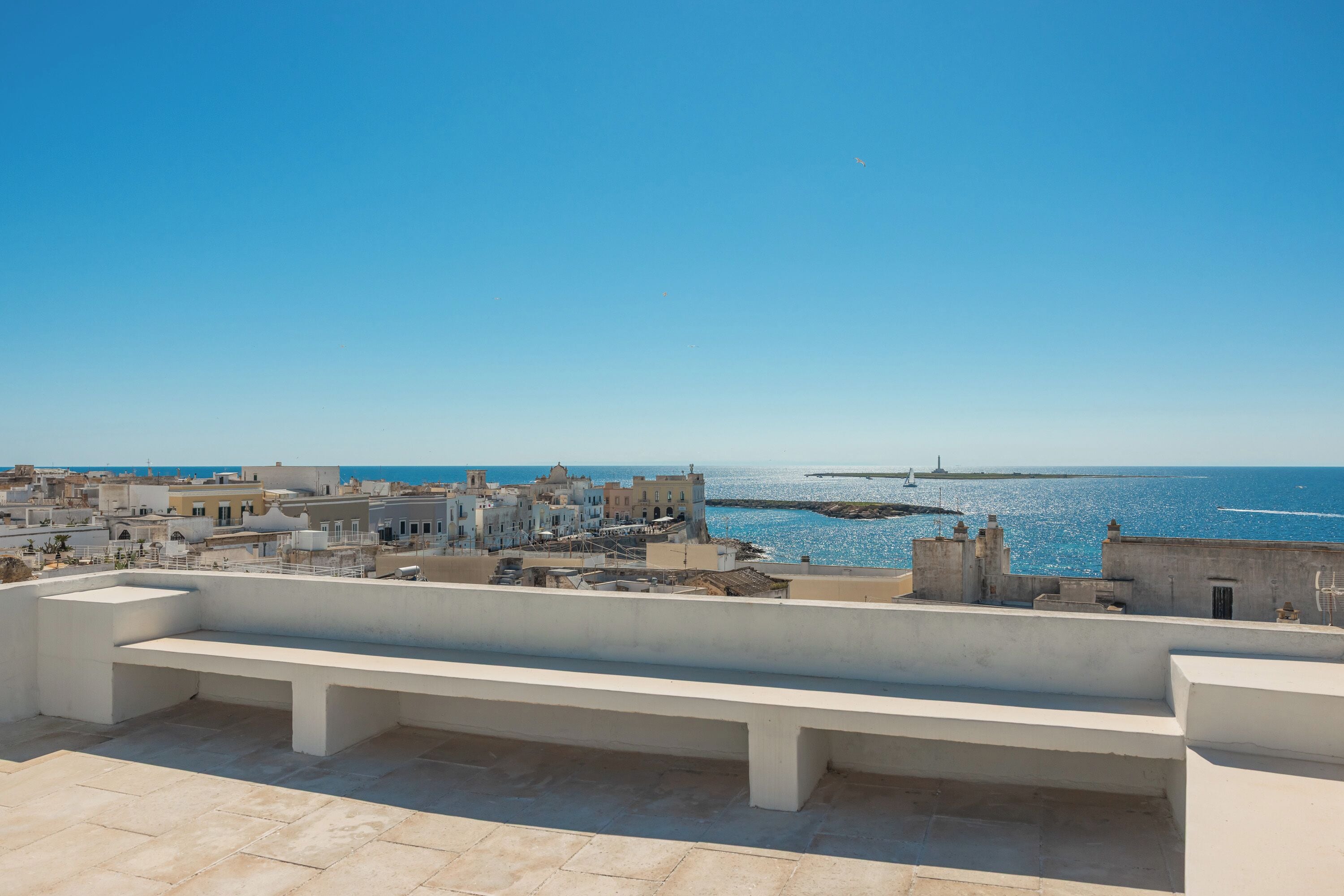 A coastal cityscape with buildings and a clear view of the sea.