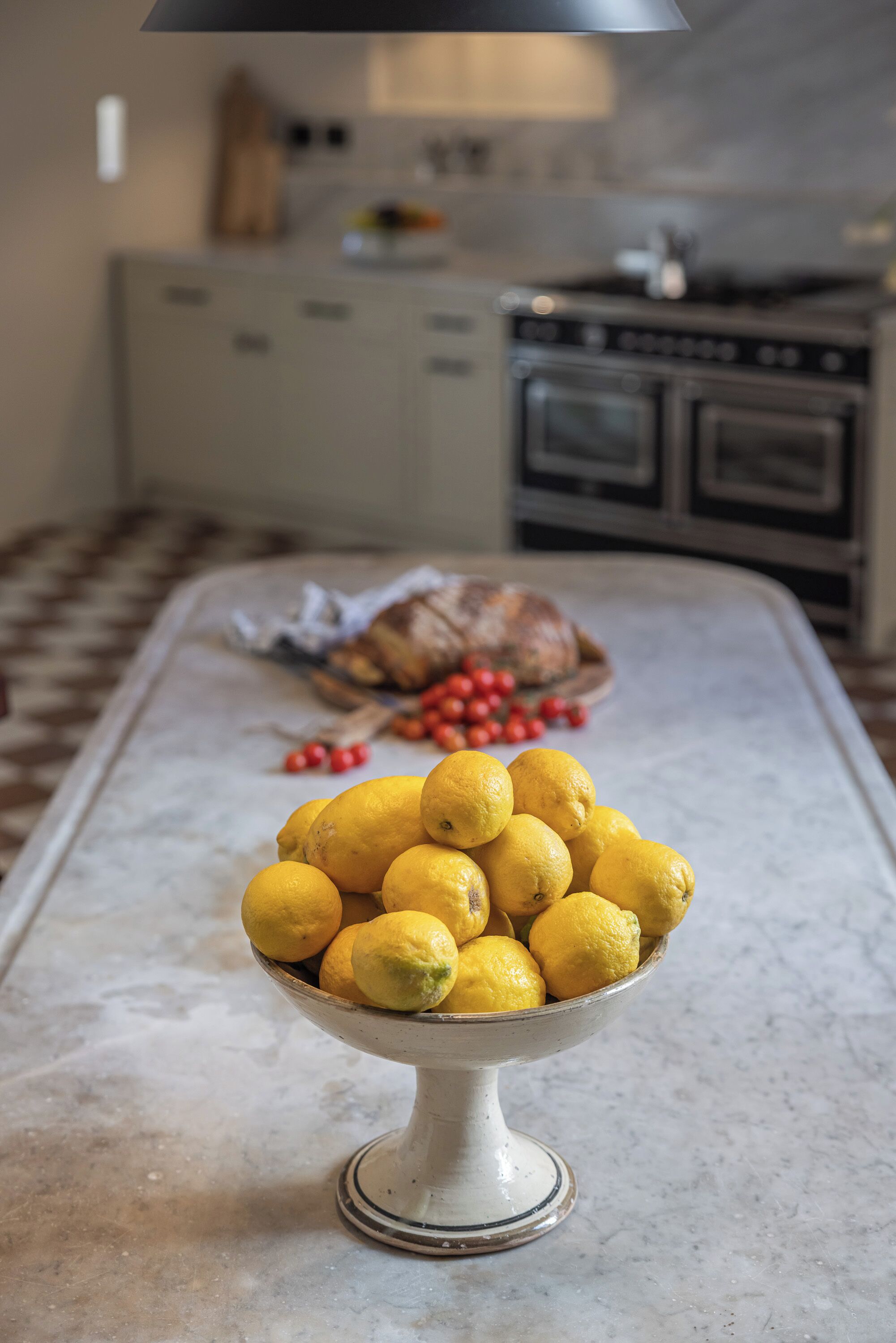 A kitchen counter with a bowl of lemons and a loaf of bread.