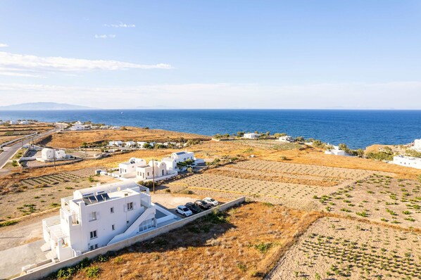 A coastal village with white buildings, a road, and fields. - Santorini's Welcoming Getaway - Blissful & Homely (Pori)