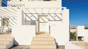 A white building with a staircase leading to a door, a pool, and a clear blue sky. - Santorini's Welcoming Getaway - Blissful & Homely (Pori)