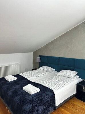 A bedroom with a bed, nightstand, lamp, and a radiator. - Florianska DeLux Annex 2-bedroom apartment with AC in Old Town Kraków (Kraków)