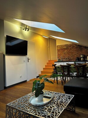 A modern kitchen with a TV, wooden staircase, and a dining area with chairs and a table. - Florianska DeLux Annex 2-bedroom apartment with AC in Old Town Kraków (Kraków)