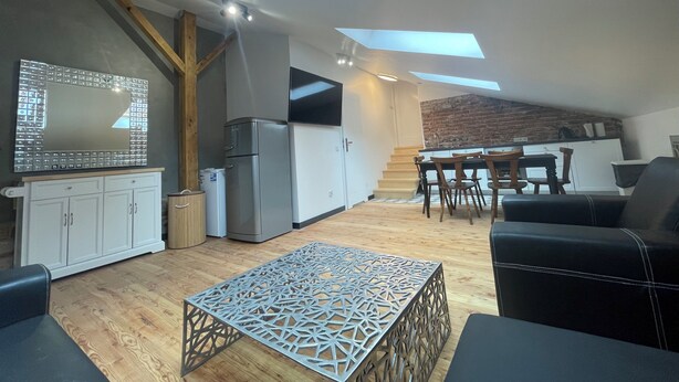 A modern kitchen with a skylight, a dining area with a table and chairs, and a living space with a sofa and a decorative table. - Florianska DeLux Annex 2-bedroom apartment with AC in Old Town Kraków (Kraków)