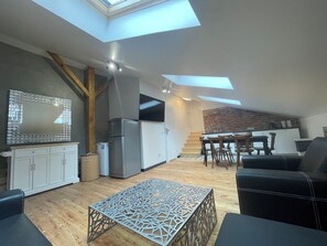 A modern kitchen with a skylight, a dining area with a table and chairs, and a living space with a sofa and a decorative table. - Florianska DeLux Annex 2-bedroom apartment with AC in Old Town Kraków (Kraków)