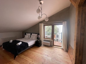 Een slaapkamer met een bed, een radiator, een raam met gordijnen en een plafondlamp.