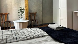 A bedroom with a bed, two chairs, a small table, a potted plant, and a wardrobe. - Florianska DeLux Annex 2-bedroom apartment with AC in Old Town Kraków (Kraków)