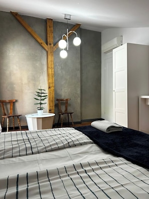 A bedroom with a bed, two chairs, a small table, a potted plant, and a wardrobe. - Florianska DeLux Annex 2-bedroom apartment with AC in Old Town Kraków (Kraków)