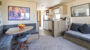 A compact living space with a kitchenette, a dining area with a table and chairs, and a seating area with a sofa.