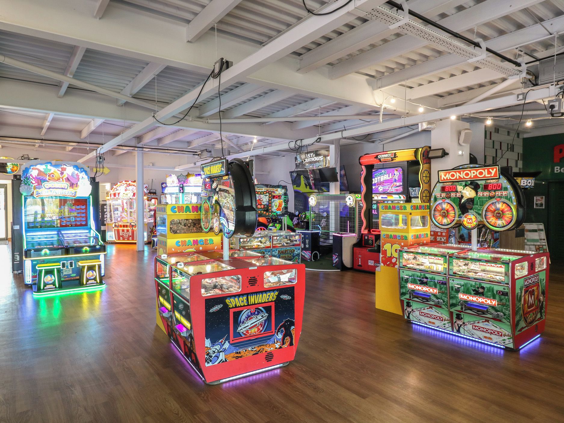 Verschiedene Spielautomaten in einem hell erleuchteten Innenraum mit Holzboden.