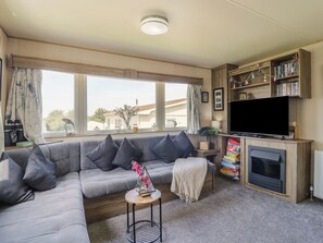 Una sala de estar con un sofá modular, televisión, chimenea y estantería.