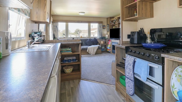 A compact kitchen with a sink, stove, and wooden cabinets.
