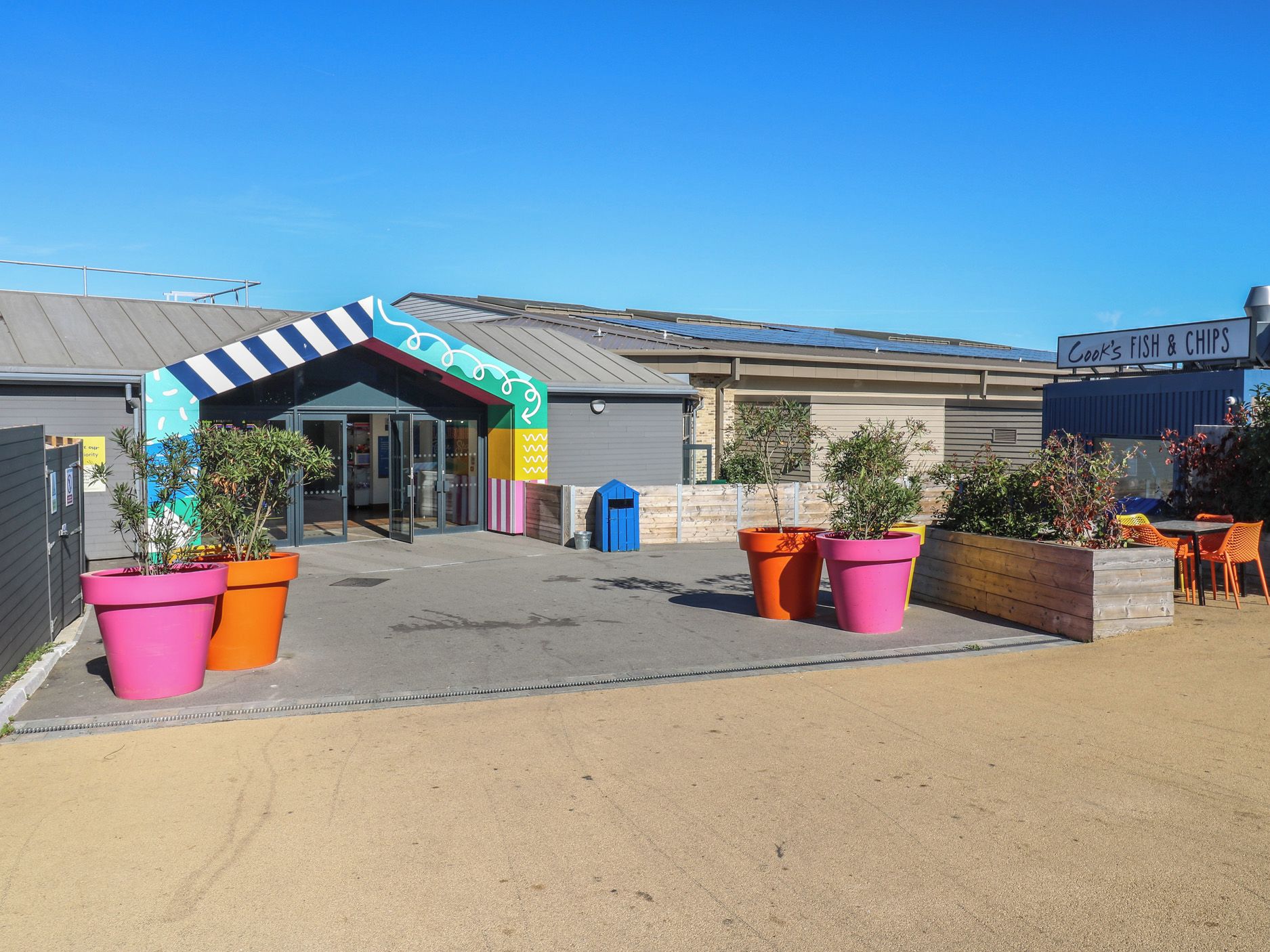 Un edificio comercial con un toldo colorido y un letrero que dice 'Cook's Fish & Chips'.