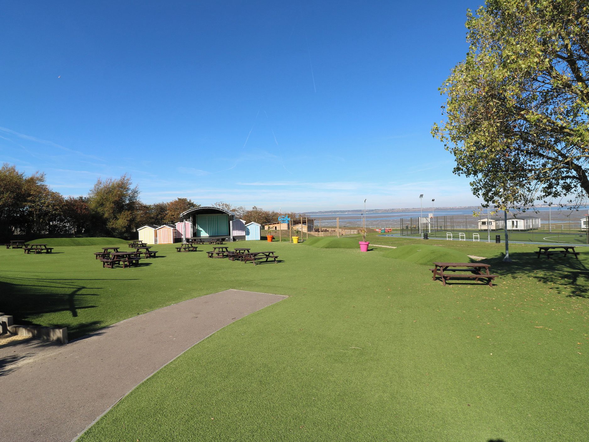 Een park met picknicktafels, een speelplaats en een klein gebouw met de tekst 'Creative Studio'.