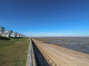 A coastal area with a sandy beach and a row of modern buildings. - Estuary View (Rochester)