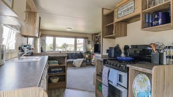 Cocina compacta para vehículos recreativos, con estufa, horno y zona de comedor con sofá.