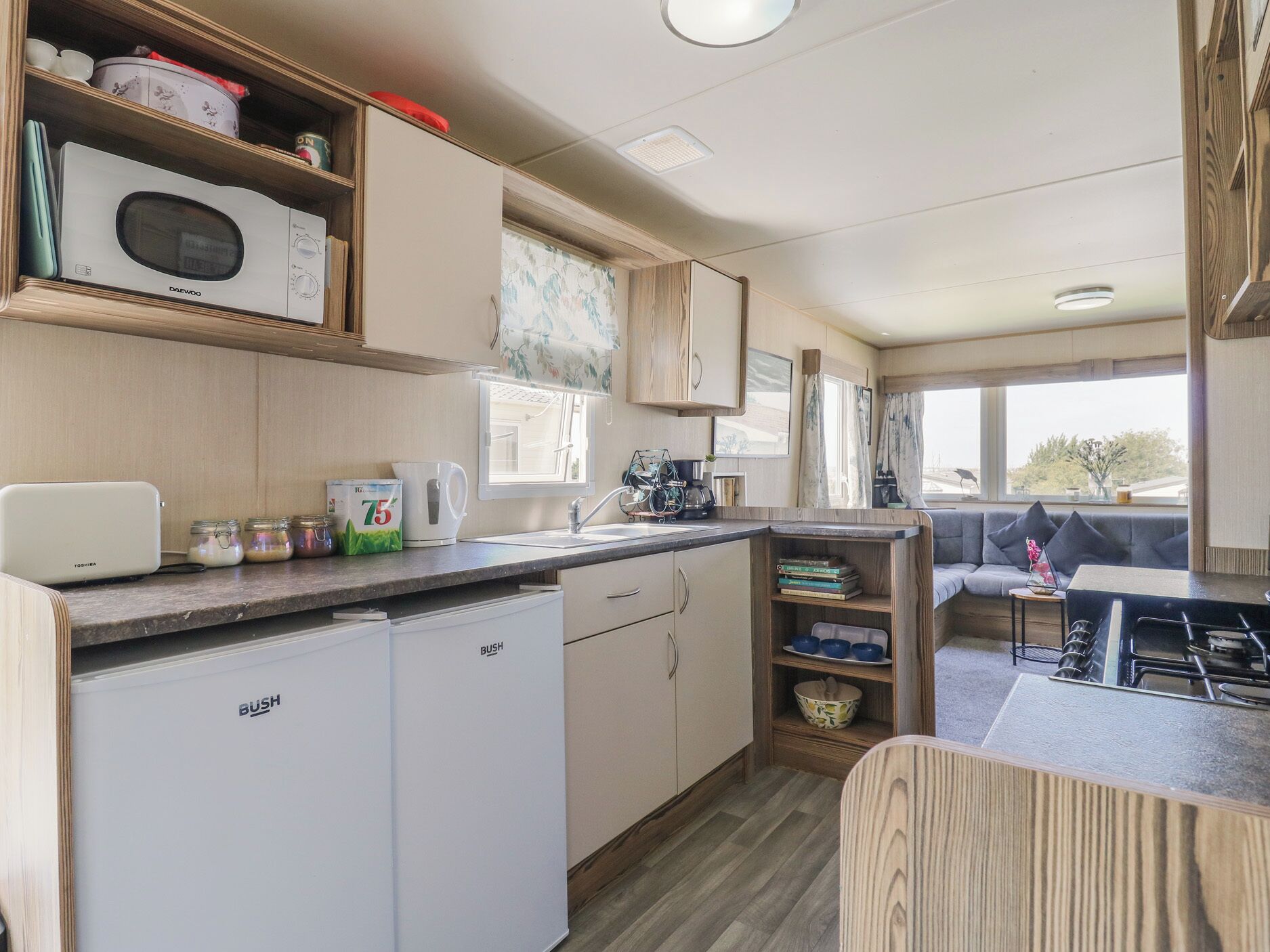 A compact kitchen with a refrigerator, microwave, and sink. There are cabinets above the counter and a window providing natural light.