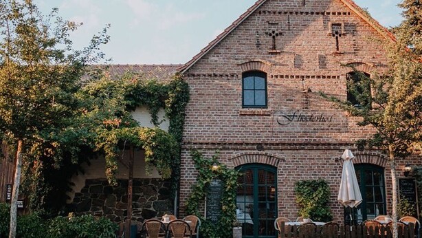 En murstensbygning med et stejlt tag, et synligt vindue og et skilt med teksten 'First Hotel'.