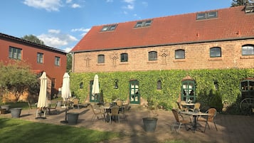 Une cour avec des espaces de repos en plein air, des bâtiments en briques et un ciel dégagé.
