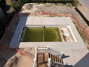 Ein Schwimmbecken mit Holzterrasse und weißer Brüstung.