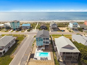 Un quartier résidentiel situé sur la côte, avec des maisons, une piscine et une plage en arrière-plan.