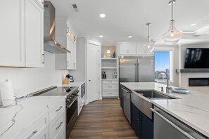 Une cuisine moderne avec des meubles blancs, des appareils électroménagers en acier inoxydable et un plancher en bois.