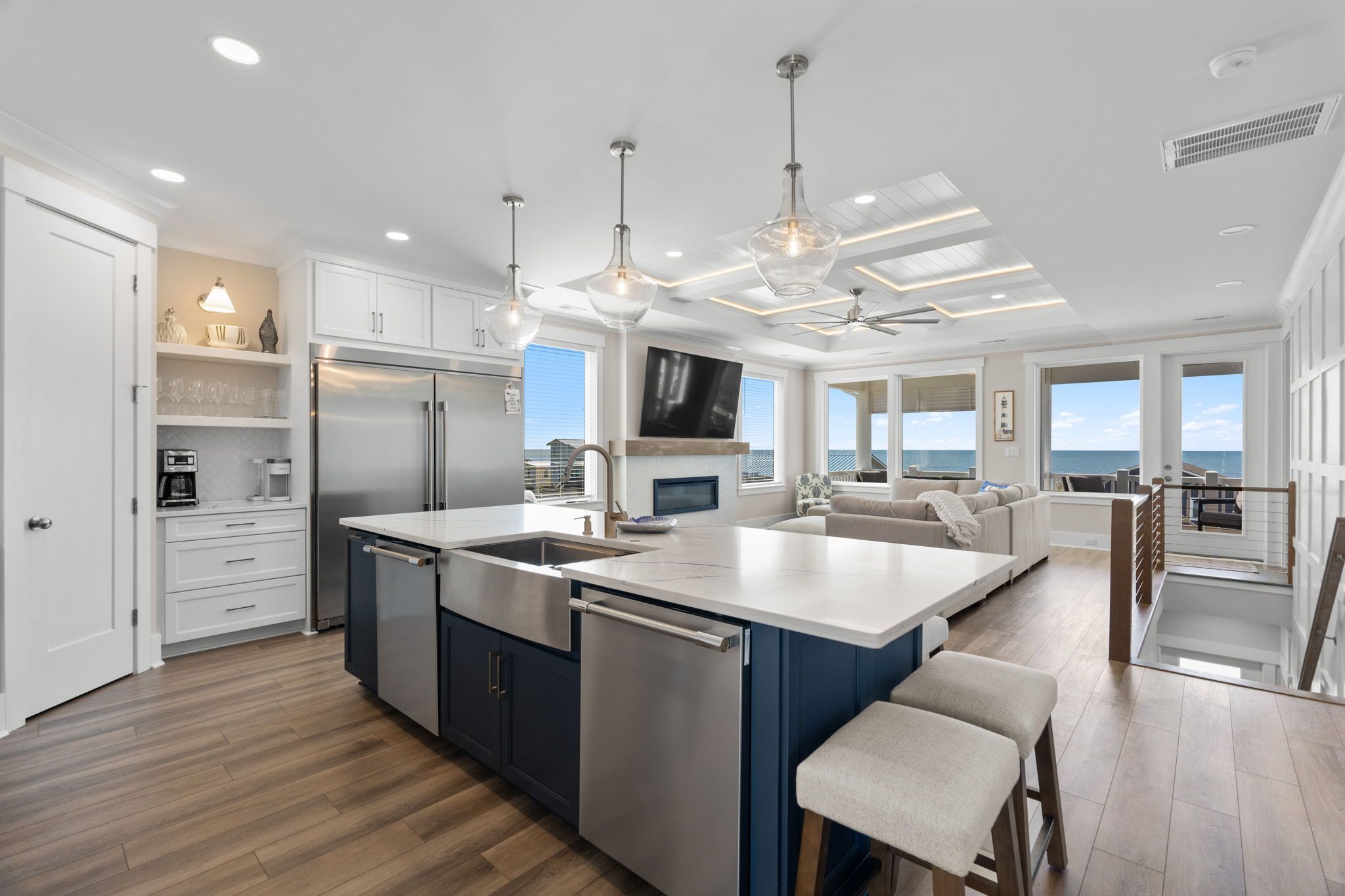 A modern kitchen with a central island, stainless steel appliances, and a view to the outside.